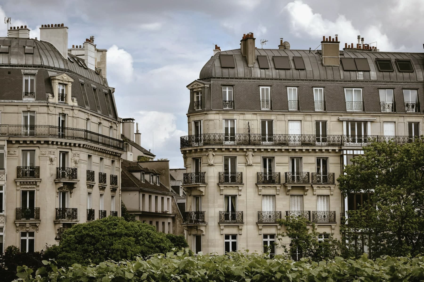 Paris apartment buildings with wrought-iron balconies beneath a cloudy sky